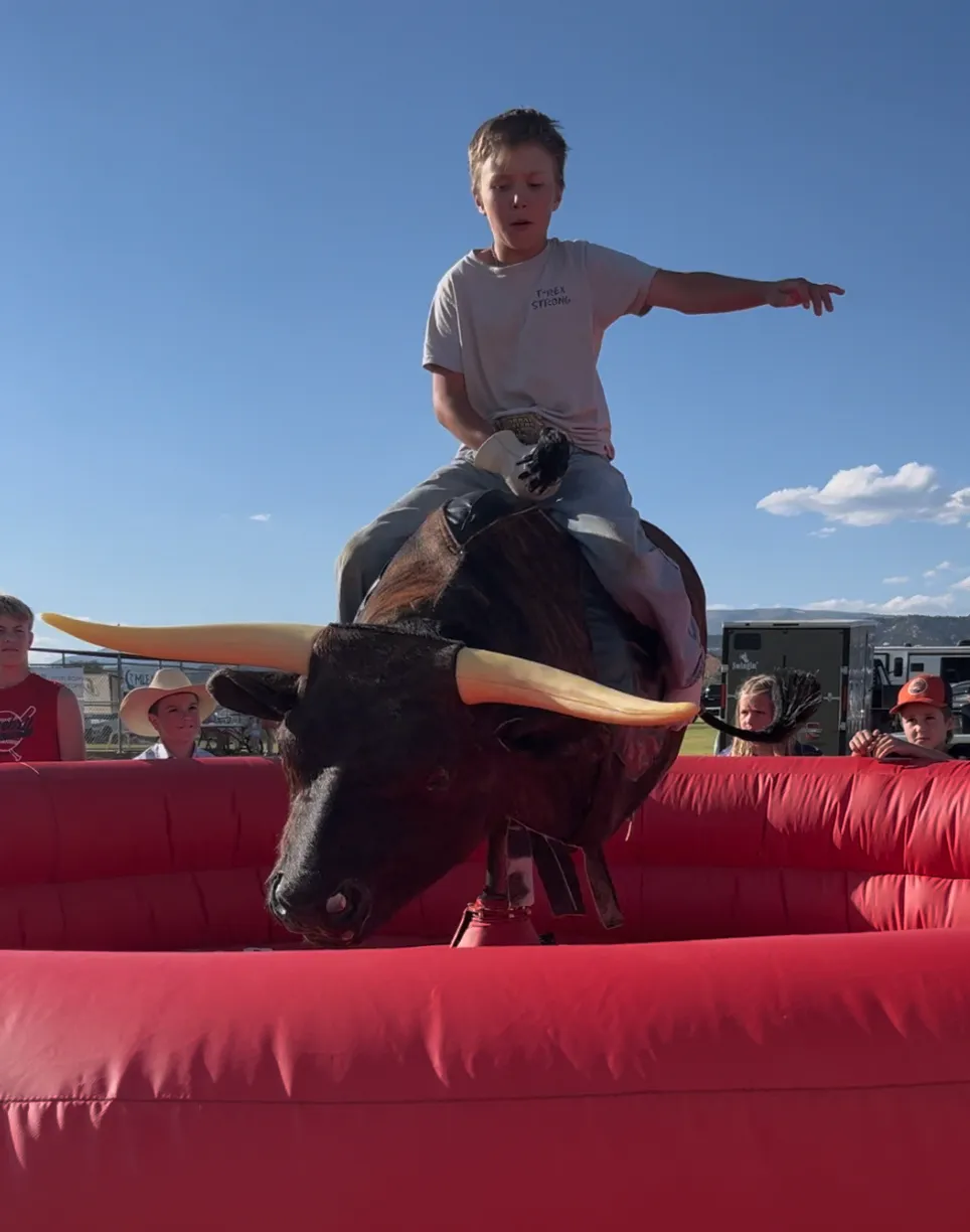 Kid riding mechanical bull outdoors at a Utah community event